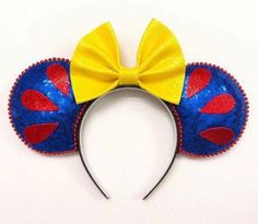 a mickey mouse ears headband with a yellow bow on it's side and red, blue, and yellow sequins around the ears