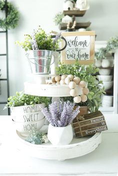 a three tiered tray with eggs and flowers on it in front of a sign that says welcome to our home