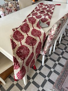 a dining room table covered with a red and white quilted runner next to two chairs