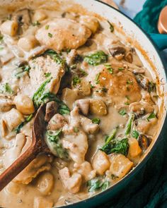 a skillet filled with chicken, dumplings and spinach covered in gravy