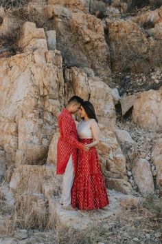 a man and woman standing next to each other near rocks