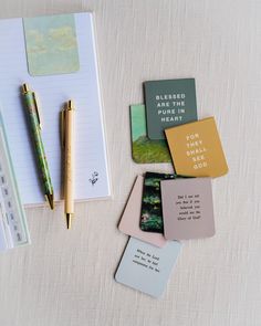 notebooks, pens and sticky notes are on a table with a notepad next to them