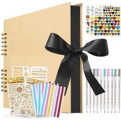 an open notebook with black ribbon and various stationery items including pens, markers, stickers