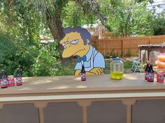 the simpsons character is sitting on top of an outdoor bar with beer bottles and cans