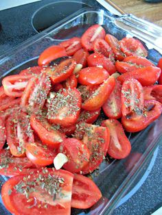 sliced tomatoes in a plastic container with seasoning on top, ready to be cooked