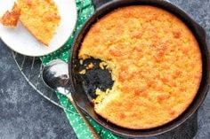 a skillet with a piece of cake in it next to a plate and spoon