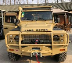 a yellow land rover vehicle parked in front of a building with other vehicles behind it