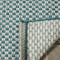 blue and white rugs with different patterns on the floor, one is folded in half