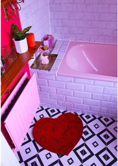 a pink bath tub sitting next to a red heart shaped rug