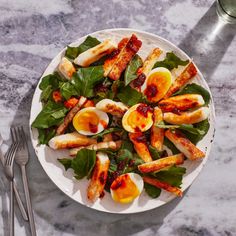 a white plate topped with sliced eggs and spinach on top of a table next to utensils