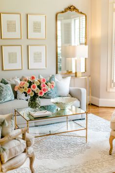 a living room filled with furniture and flowers on top of a coffee table in front of a mirror