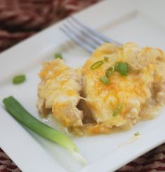 a white plate topped with an egg casserole and green onions next to a fork