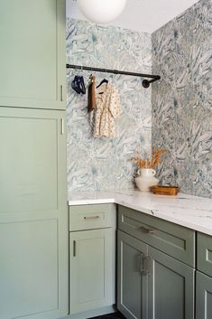 a kitchen with blue and green wallpaper, white counter tops and cabinets in the corner