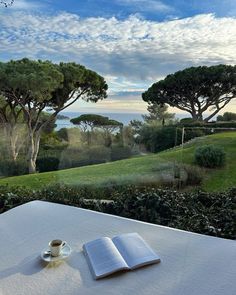 an open book sitting on top of a table next to a cup and saucer