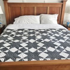 a bed with white and black quilts on it in a bedroom next to two nightstands