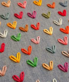 many different colored pieces of fabric on a table cloth with scissors in the middle and one being cut into small hearts