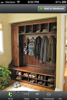 a coat rack with shoes and coats hanging on it in front of a window next to a potted plant