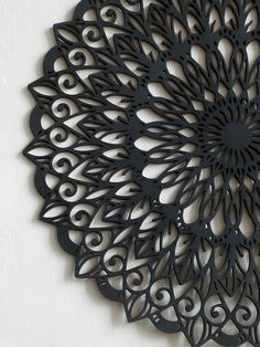 an intricate metal wall hanging on the side of a white wall with a clock in it