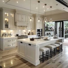 a large kitchen with white cabinets and an island in the middle is lit by pendant lights