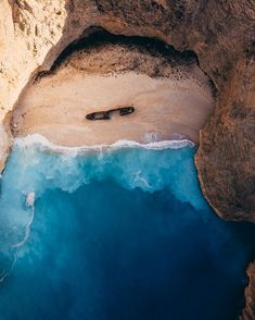 an aerial view of a beach with a boat in the water and cliffs on either side