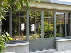 a house with many windows and plants in the yard