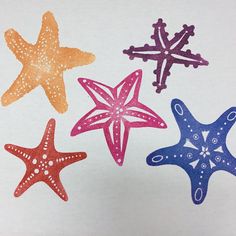 four different colored starfishs on white paper