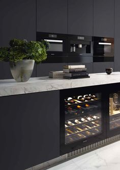 a kitchen with black cabinets and marble counter tops, an oven is open to show baked goods