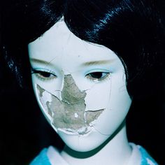 a close up of a doll's face with a piece of paper on it