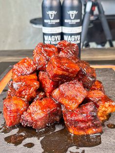 a pile of meat sitting on top of a cutting board next to two beer bottles