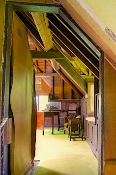 an open door leading to a room with wooden walls and ceiling beams in the attic