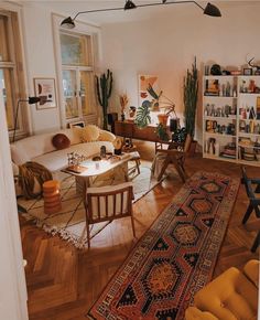 a living room filled with lots of furniture and decor on top of a hard wood floor