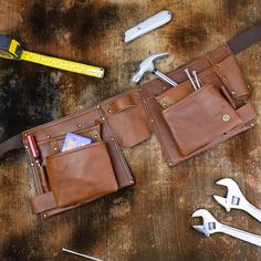 a leather tool bag with tools and wrenches laying on the table next to it