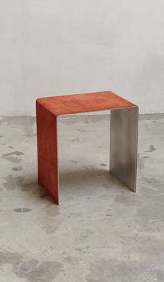 an orange bench sitting on top of a cement floor