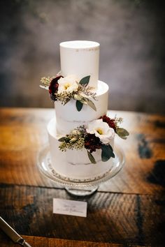 a three tiered wedding cake with flowers on it and a knife next to it