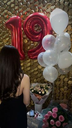 a woman standing in front of balloons and flowers