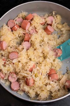 a pan filled with rice and sausages on top of a stove next to a blue spatula