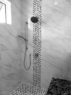 black and white photograph of a shower in a bathroom with marble tile on the walls