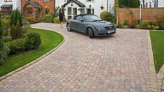 a car is parked in front of a house with a driveway and brick pavers