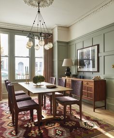 a dining room table with chairs and a chandelier hanging from it's ceiling