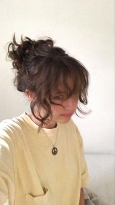 a woman sitting on top of a bed with her hair in a messy updo