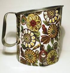 a metal mug with flowers painted on the outside and inside, sitting on a white surface