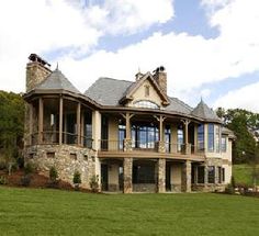 a large stone and wood house in the middle of a field