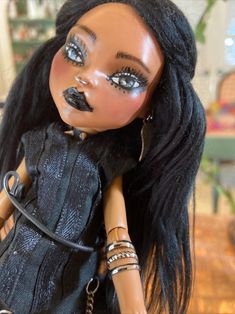 a close up of a doll with black hair and jewelry on it's face