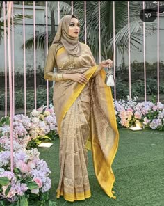 a woman standing in front of flowers wearing a sari