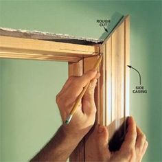 a person holding a pencil and pointing to the side of a window frame with wood framing