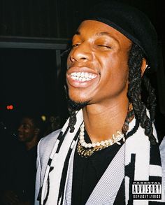 a close up of a person wearing a hat and jacket with dreadlocks on