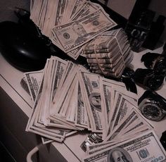 a pile of money sitting on top of a counter next to a phone and alarm clock