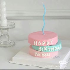 two birthday cakes sitting on top of each other with candles in the shape of letters