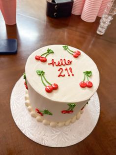 a white cake with cherries and the words hello 21 on it sitting on a table