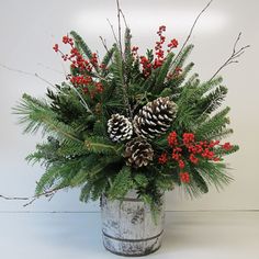 a vase filled with pine cones and red berries